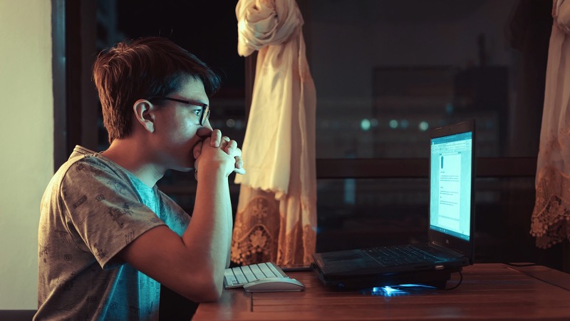 ノートパソコンの前に座る茶色のシャツを着た女性