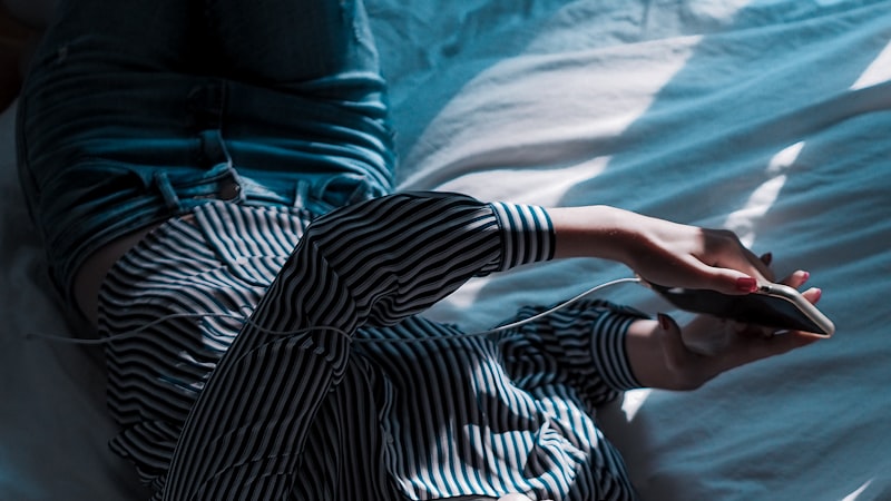 ベッドに横たわる黒と白のストライプの長袖シャツを着た女性